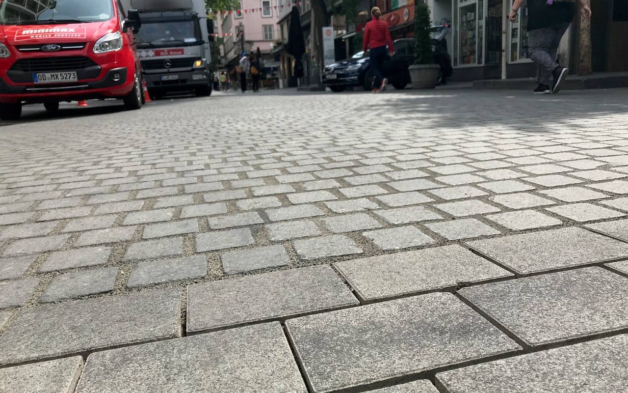 Das Bodenpflaster der Bolkerstraße. Im Hintergrund stehen LKW.