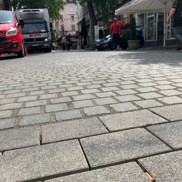 Das Bodenpflaster der Bolkerstraße. Im Hintergrund stehen LKW.