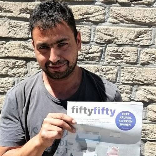 Ein fiftyfifty-Verkäufer hält ein fiftyfifty-Magazin in der Hand.