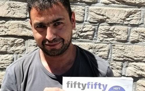 Ein fiftyfifty-Verkäufer hält ein fiftyfifty-Magazin in der Hand.