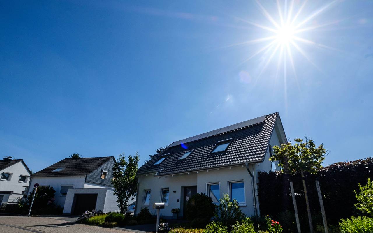 Wohnhaus mit Solaranlage auf dem Dach. Im Hintergrund sind zwei weitere Häuser zu sehen.