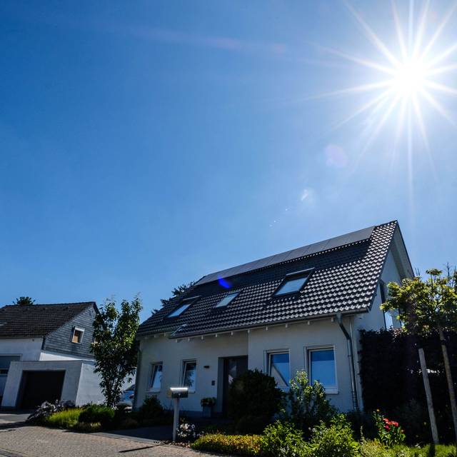 Wohnhaus mit Solaranlage auf dem Dach. Im Hintergrund sind zwei weitere Häuser zu sehen.