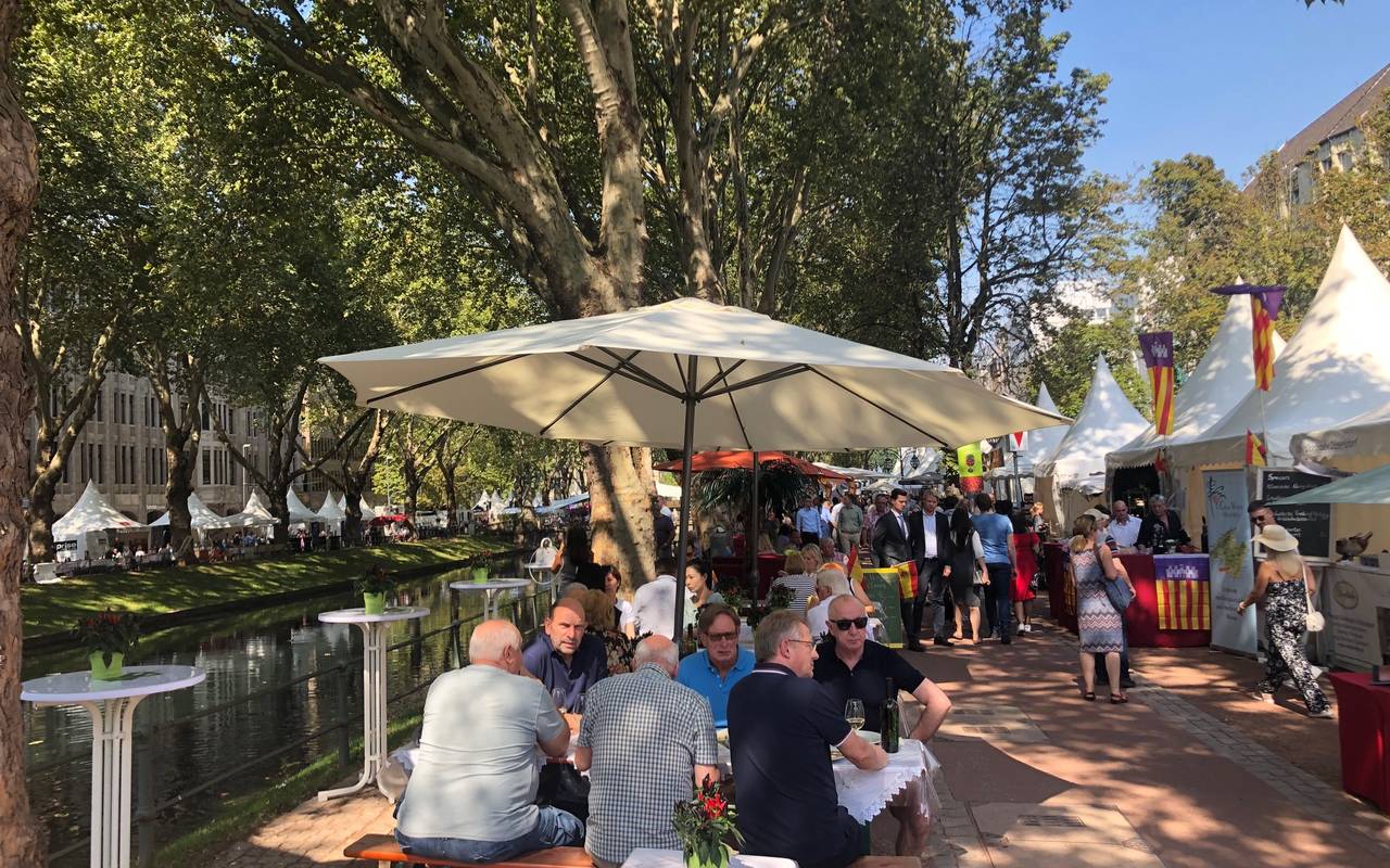 Mehrere Menschen sitzen auf Bierbänken, im Hintergrund ist der Kögraben zu sehen. Es ist das Gourmet Festival.