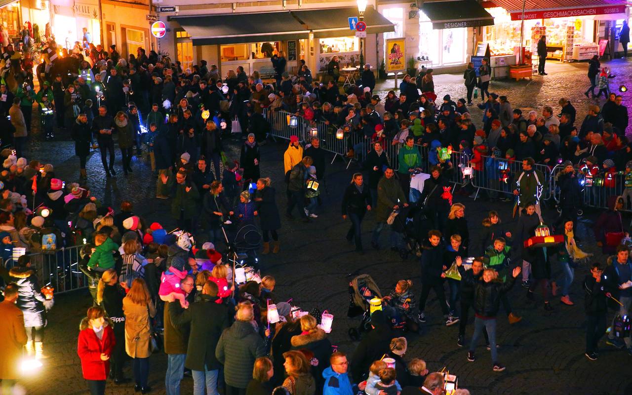 Auf dem Marktplatz warten Kinder mit leuchtenden Laternen auf St. Martin und die Mantelteilung.