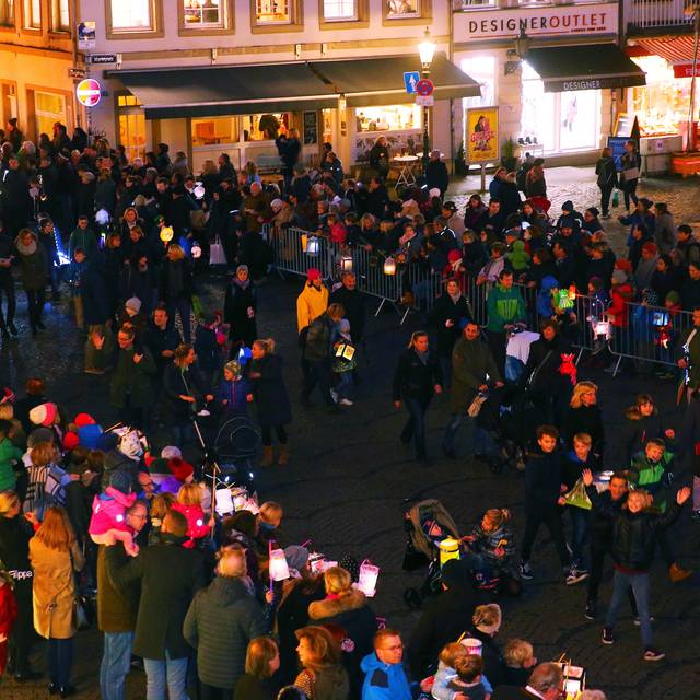 Auf dem Marktplatz warten Kinder mit leuchtenden Laternen auf St. Martin und die Mantelteilung.