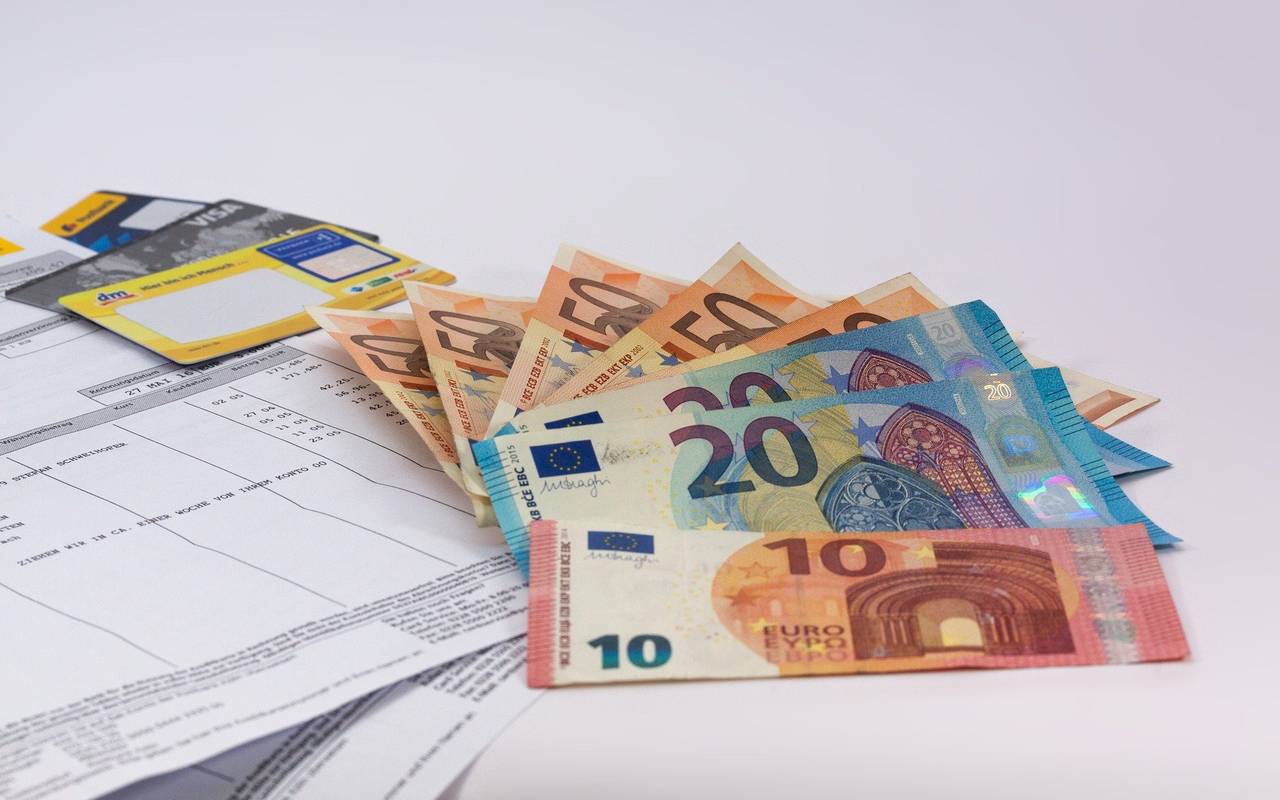 Geldscheine liegen auf einer weißen Fläche. Zu sehen sind auch Rechnungen und EC- und Kreditkarten.
