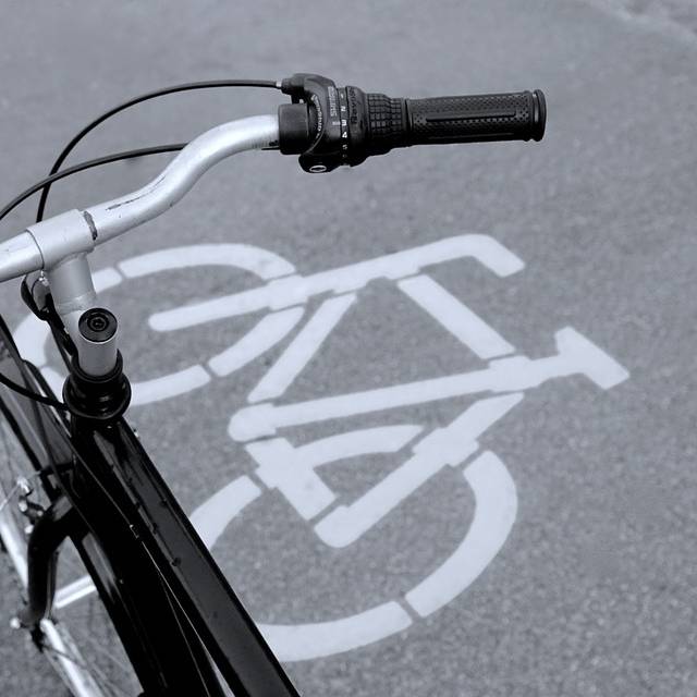 Der Lenker eines Fahrrades. Im Hintergrund ist ein Fahrrad-Symbol auf dem Boden zu sehen.