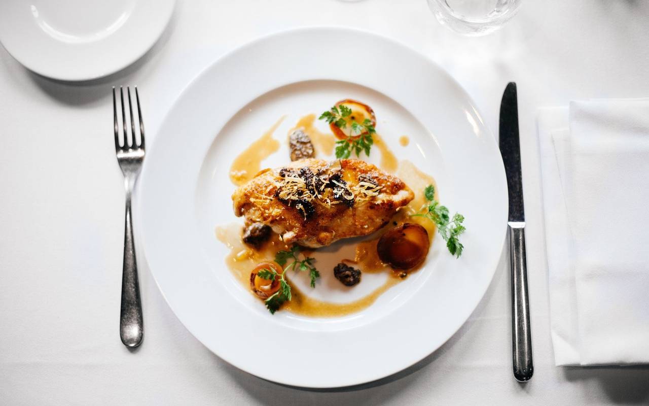 Ein schön angerichteter Teller mit Essen. Er steht auf einem gedeckten Tisch.