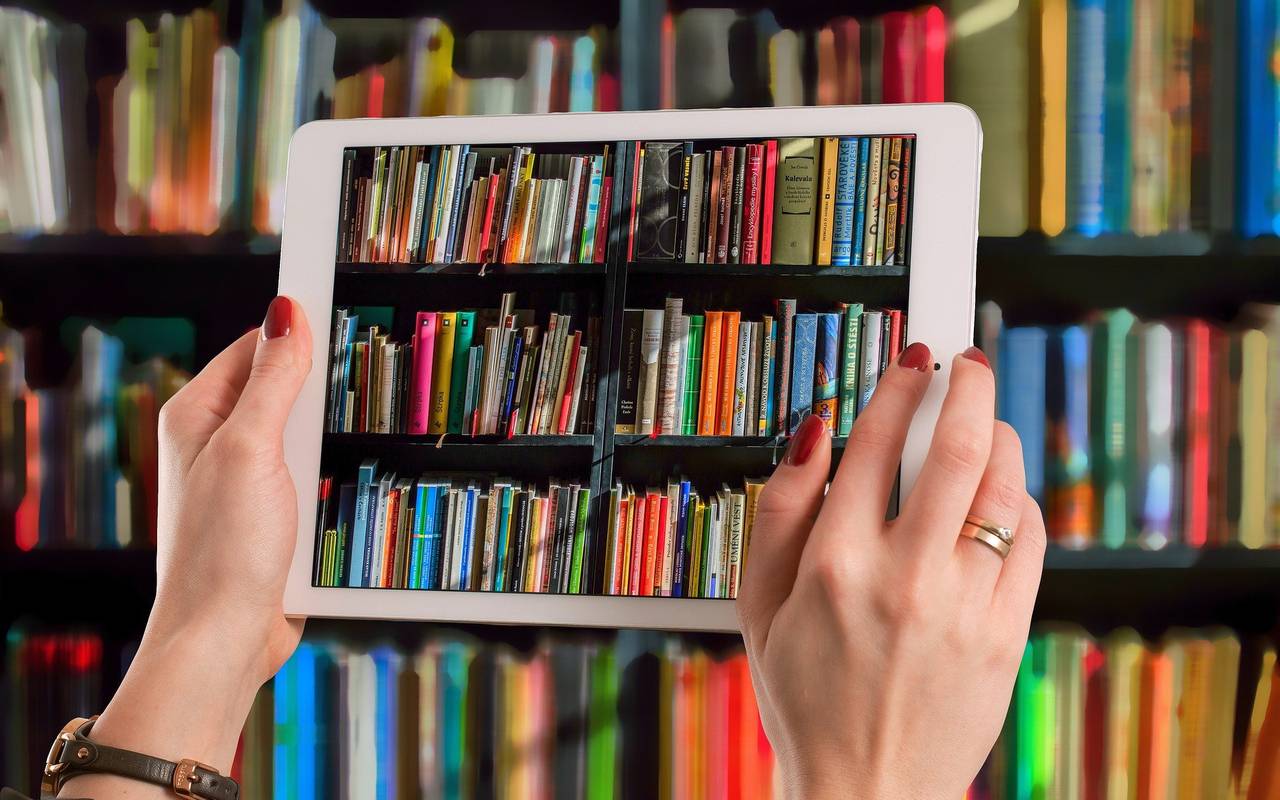 Ein Tablet, mit dem ein Bücherregal fotografiert wird.
