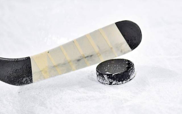 Ein Eishockeyschläger trifft einen Puck auf dem Eis.