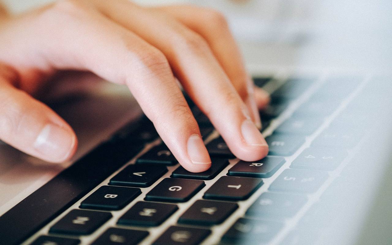 Eine linke Hand tippt auf einer Laptoptastaur.