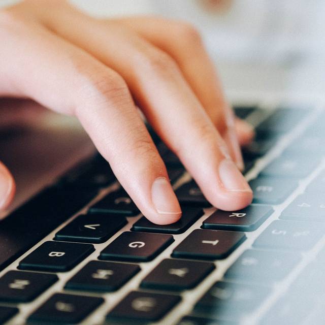 Eine linke Hand tippt auf einer Laptoptastaur.