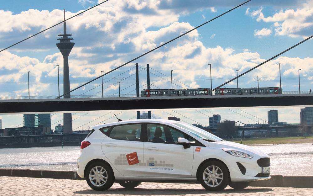Weißes Car-Sharing-Auto steht vor der Oberkasseler Brücke