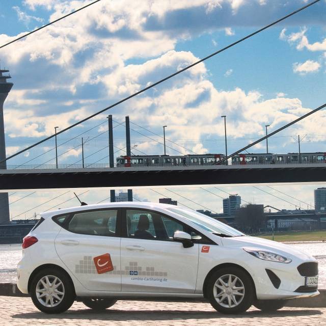 Weißes Car-Sharing-Auto steht vor der Oberkasseler Brücke