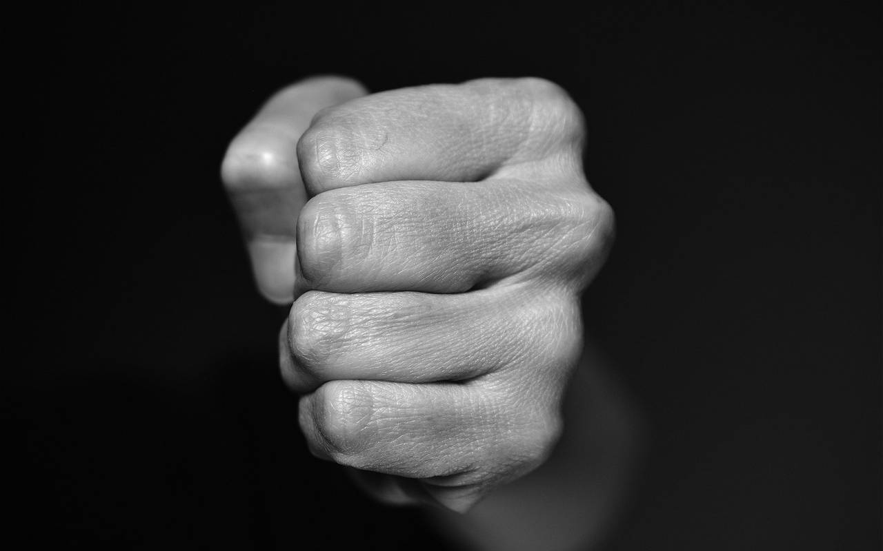 Eine zur Faust geballte Hand vor schwarzem Hintergrund.