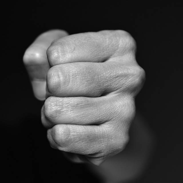 Eine zur Faust geballte Hand vor schwarzem Hintergrund.