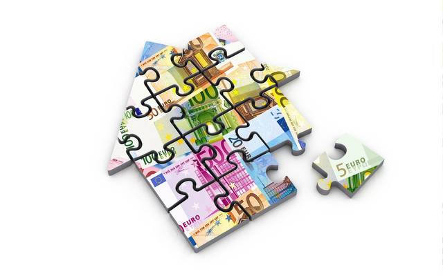 Ein Puzzle, das ein Haus zeigt. Die Motive stellen Geldscheine dar.