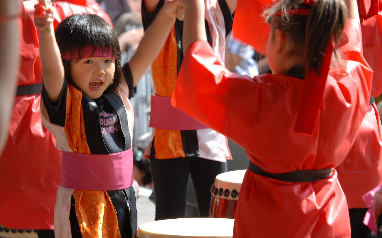 Zwei Kinder schlagen am Japan-Tag auf eine Trommel und tragen festliche Gewänder.