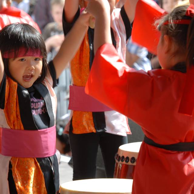 Zwei Kinder schlagen am Japan-Tag auf eine Trommel und tragen festliche Gewänder.