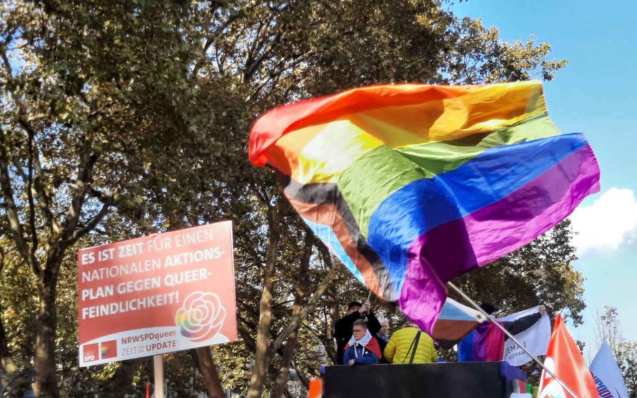 Eine Regenbogenflagge wehr bei einer Demo.