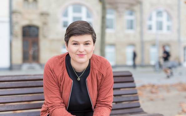 Sara Nanni vom Bündnis 90/ Die Grünen sitzt auf einer Bank und blickt in die Kamera.