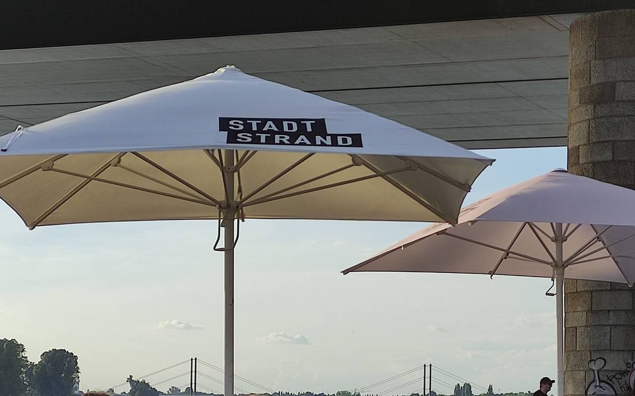 Ein geöffneter Sonnenschirm am Düsseldorfer Stadtstrand am Rhein.
