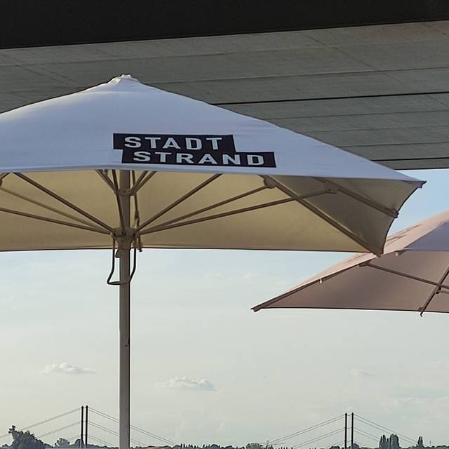 Ein geöffneter Sonnenschirm am Düsseldorfer Stadtstrand am Rhein.