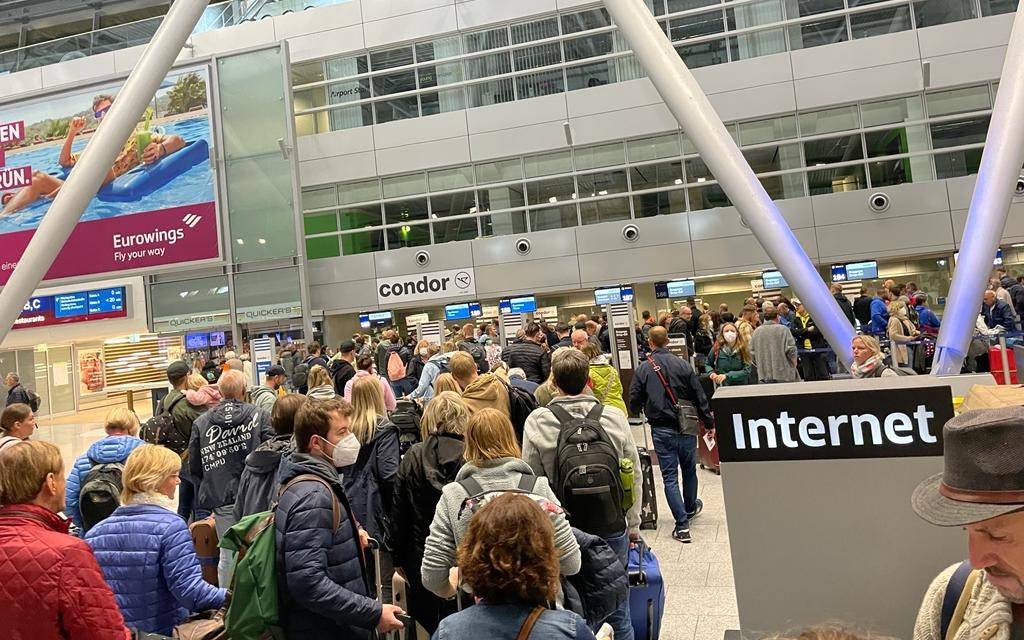 Menschen stehen am Flughafen Düsseldorf in einer langen Warteschlange.