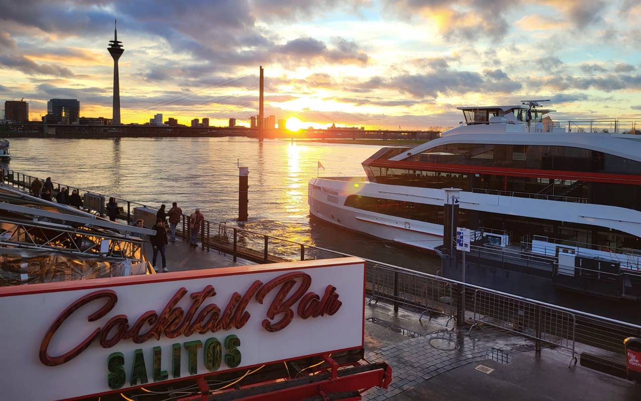 Die Rheinuferpromenade mit Sonnenuntergang und Rheinturm.