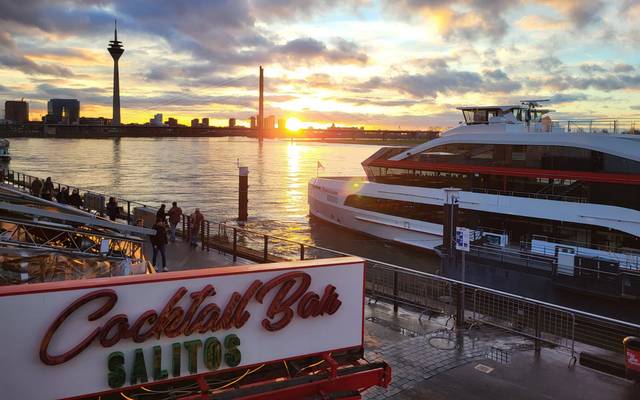 Die Rheinuferpromenade mit Sonnenuntergang und Rheinturm.
