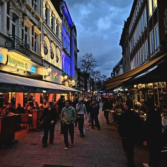 Menschen gehen am Abend durch die Altstadt über die Bolker Straße.
