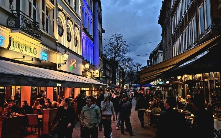 Menschen gehen am Abend durch die Altstadt über die Bolker Straße.