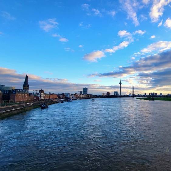 Im Vordergrund ist der Rhein zu sehen, im Hintergrund die Skyline von Düsseldorf.