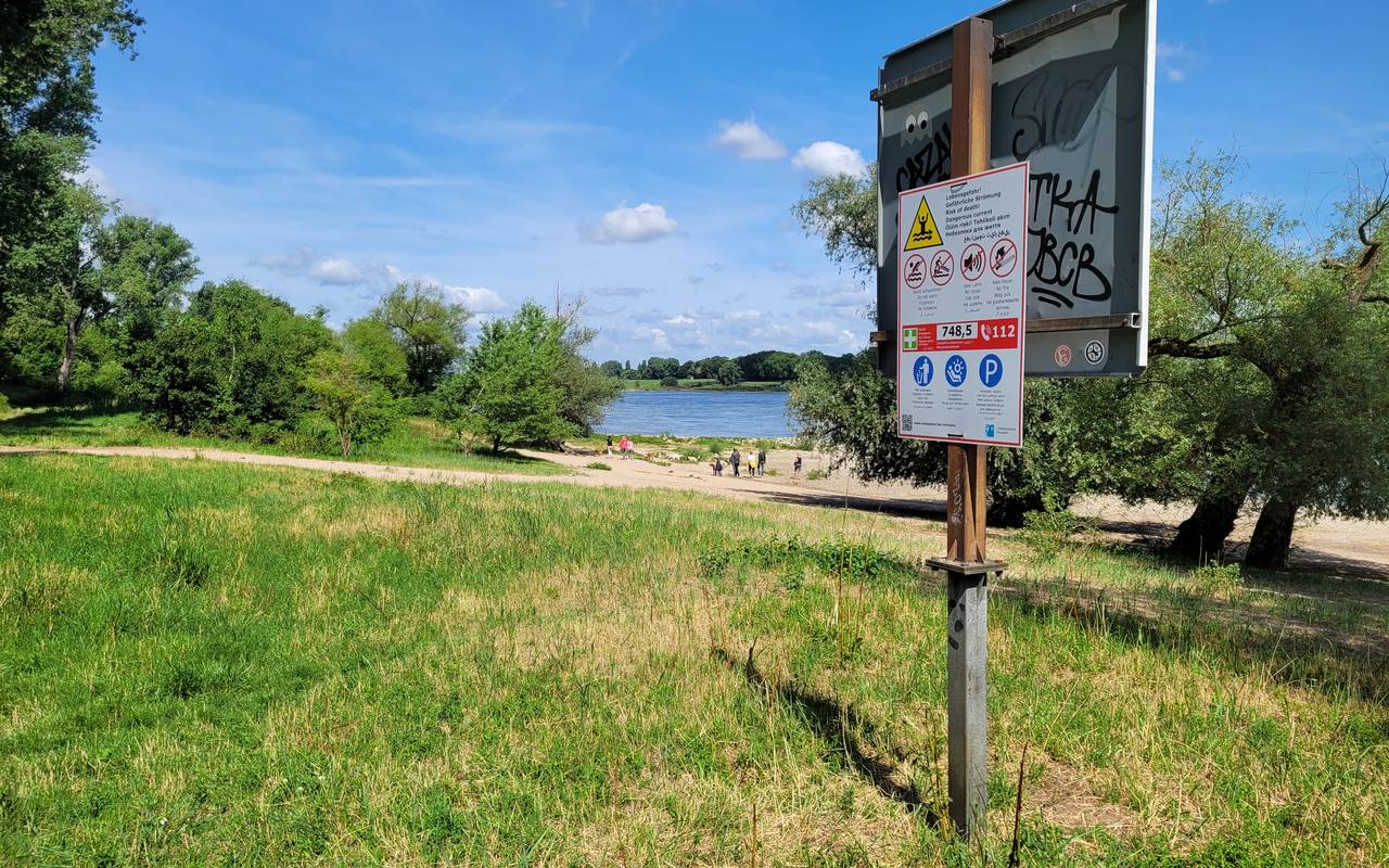 Ein Warnschild am Rhein warnt vor den Gefahren beim Schwimmen im Rhein.