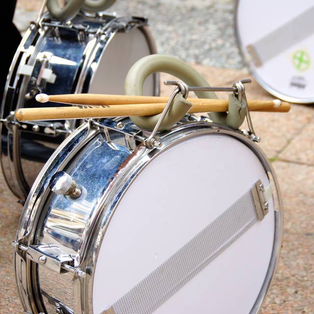 Zwei Trommeln von Menschen, die in einem Spielmannszug spielen.