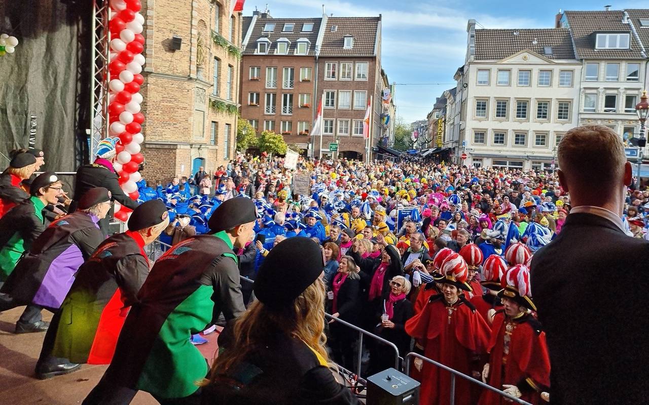 Auf dem Marktplatz vor dem Rathaus wird Karneval gefeiert. Auf einer Bühne macht die KG Regenbogen Stimmung.