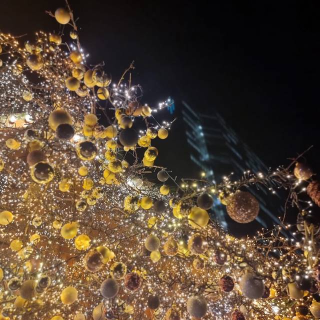 Gelber Weihnachtsschmuck und Lichter in einem Baum.