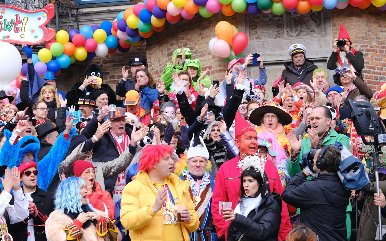 Eine vollbesetzte Tribühne vor dem Rathaus. Die Jecken feiern Rosenmontag und den Rosenmontagszug.
