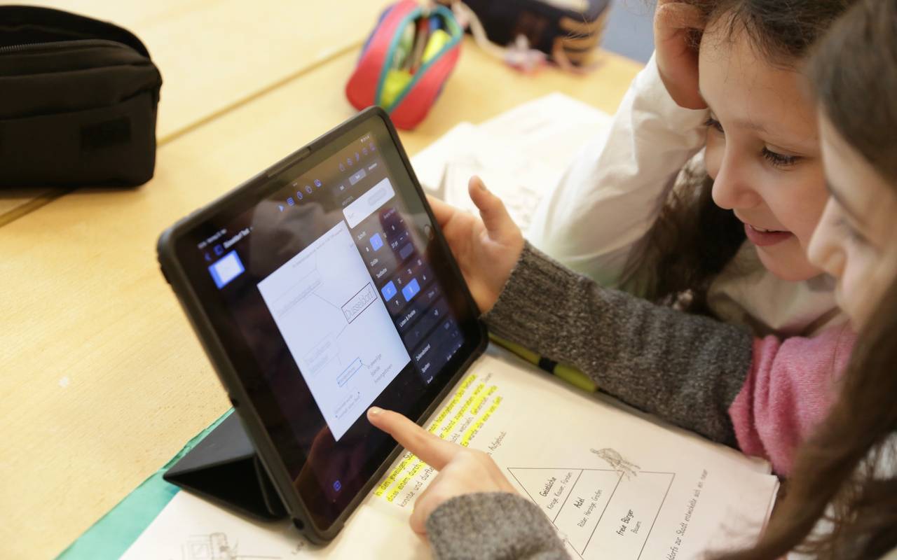 Kinder sitzen vor einem Tablet, Digitalisierung der Schulen