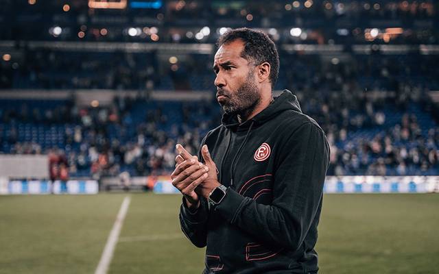 Daniel Thioune, der Fortuna-Trainer, steht auf dem Spielfeld und reibt sich die Hände.
