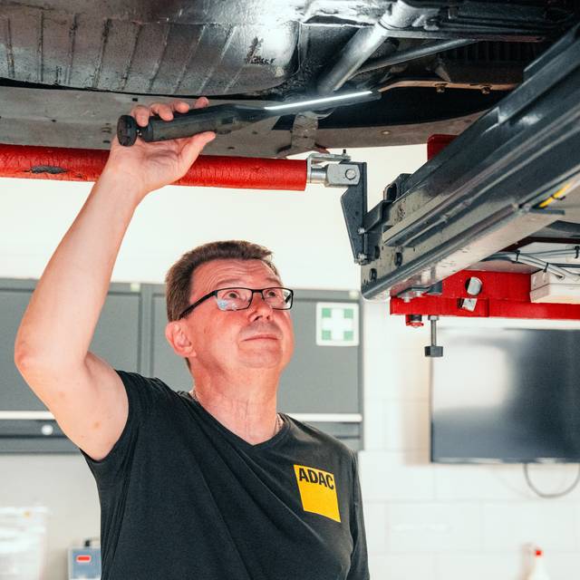 Ein Auto ist auf der Hebebühne, ein ADAC-Mitarbeiter prüft