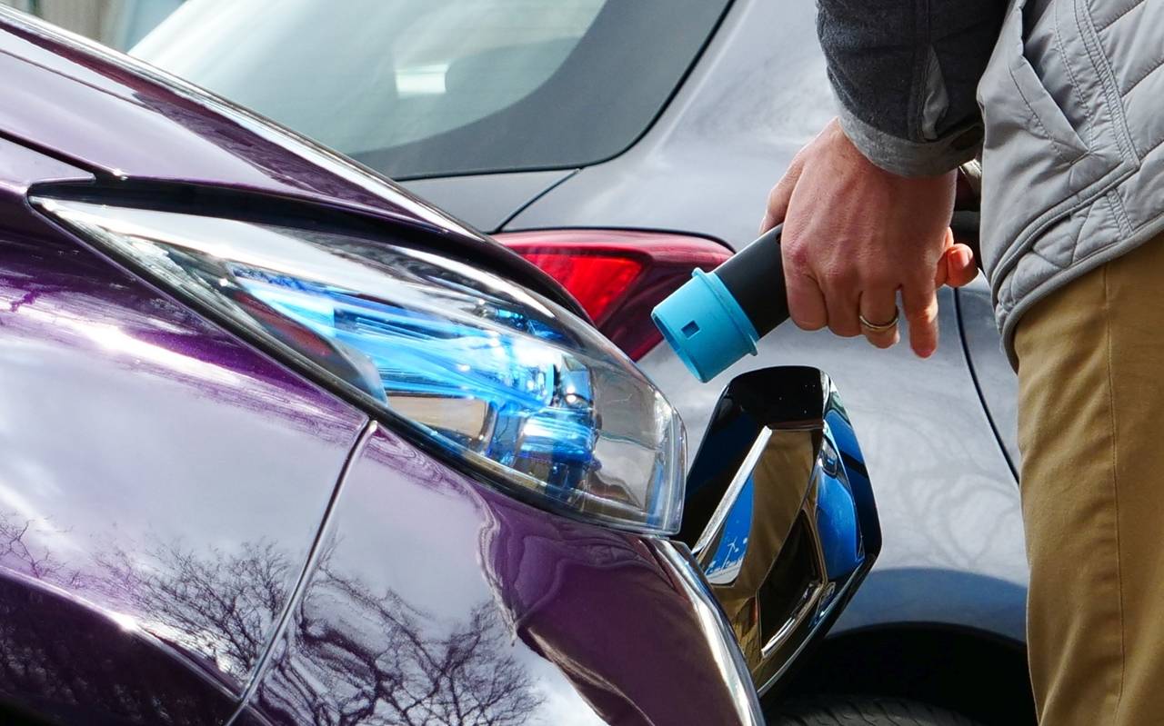 Ein Mann startet den Ladevorgang an einem Elektroauto.