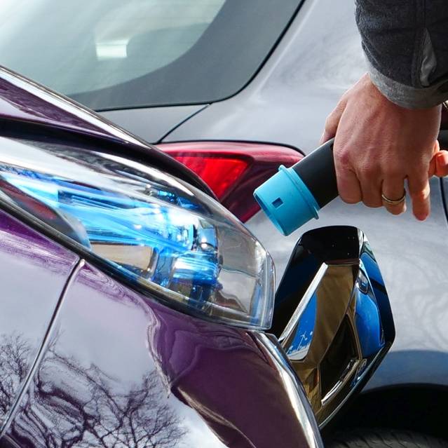 Ein Mann startet den Ladevorgang an einem Elektroauto.