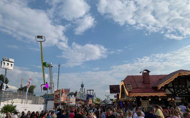 Die Rheinkirmes bei schönem Wetter. Viele Menschen schlendern über den Platz und an den Fahrgeschäften vorbei.