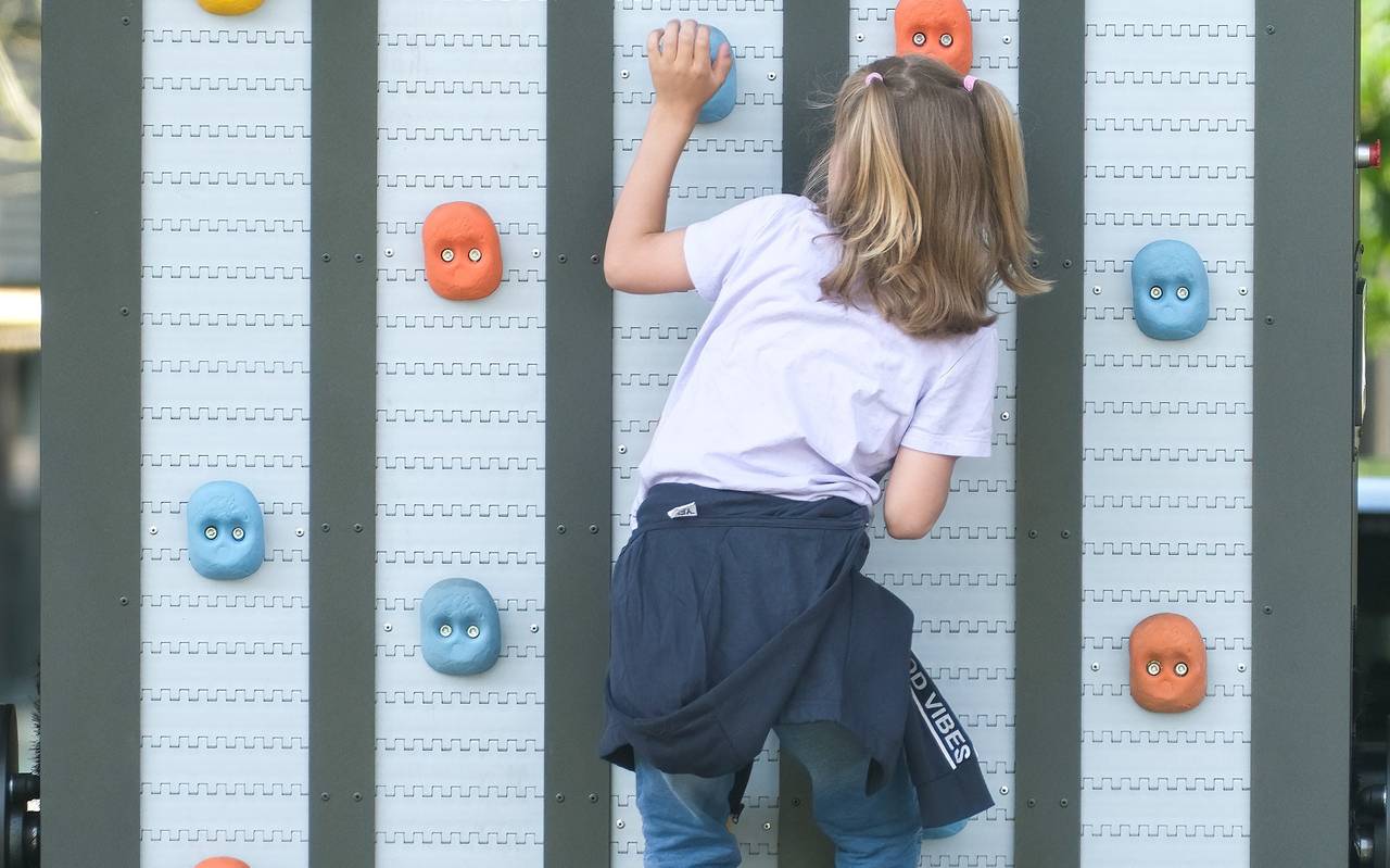 Ein Mädchen klettert an einer Kletterwand mit bunten Griffen. Das Angebot ist Teil des Olympic Adventure Camp am Rhein.