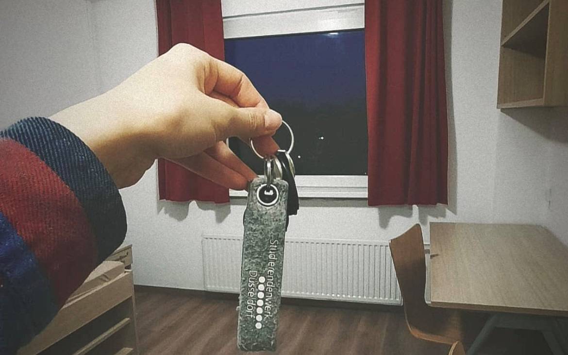 Eine Frau hält einen Schlüssel in einem Studentenzimmer.