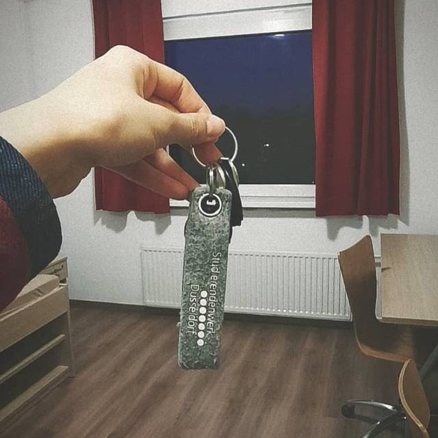 Eine Frau hält einen Schlüssel in einem Studentenzimmer.