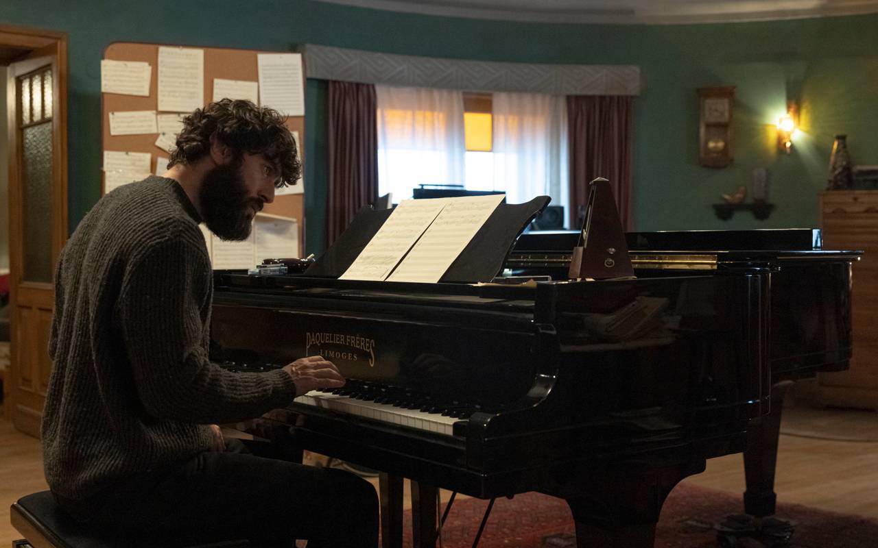 Harper sitzt am Piano.