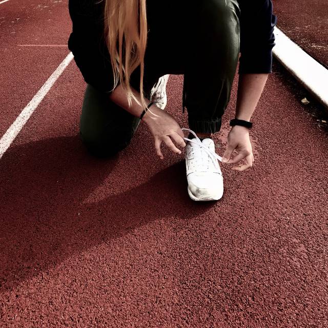 Sportler schnürt sich seinen weißen Turnschuh zum Laufen.