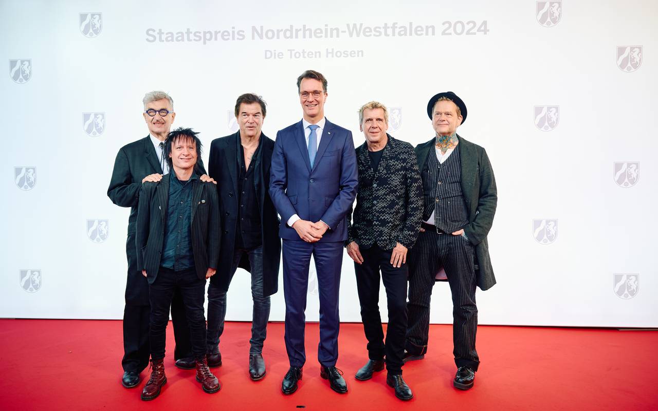 Die Toten Hosen und Ministerpräsident Hendrik Wüst stehen bei der Preisverleihung vom NRW-Staatspreis auf dem Roten Teppich.